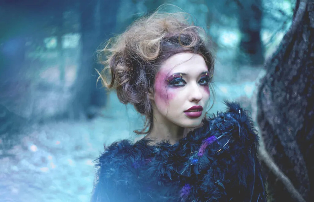 Professional female model with striking hair and makeup set in a wild wilderness scene.