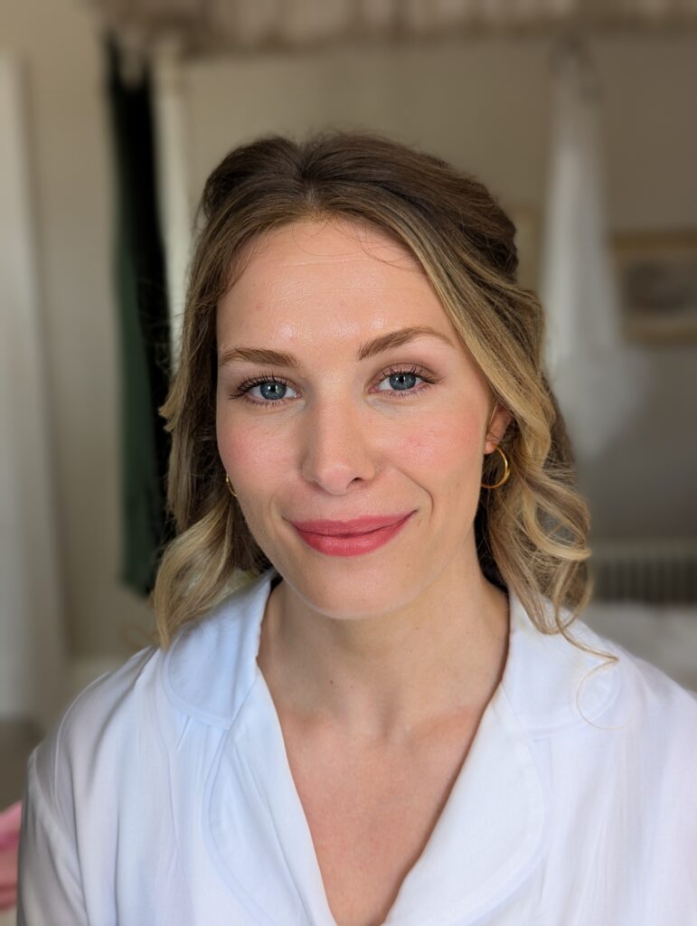 blonde woman staring into camera smiling wearing makeup