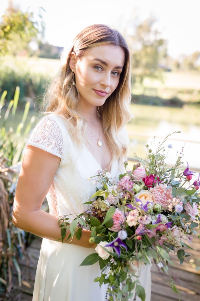 Bride holding flowers and smiling with makeup by Bristol makeup artist Evie Smith.