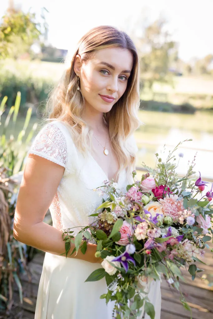 Bride holding flowers and smiling with makeup by Bristol makeup artist Evie Smith.