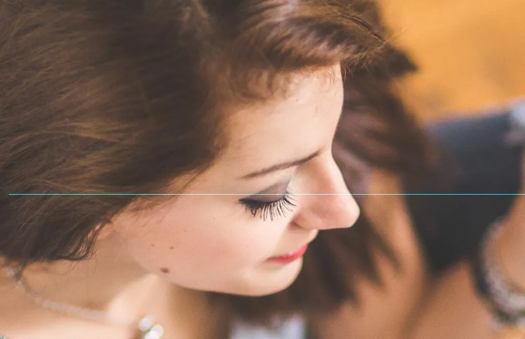 Close-up photo of a model taken from above and to the side of their head showing off their makeup and eye lashes.