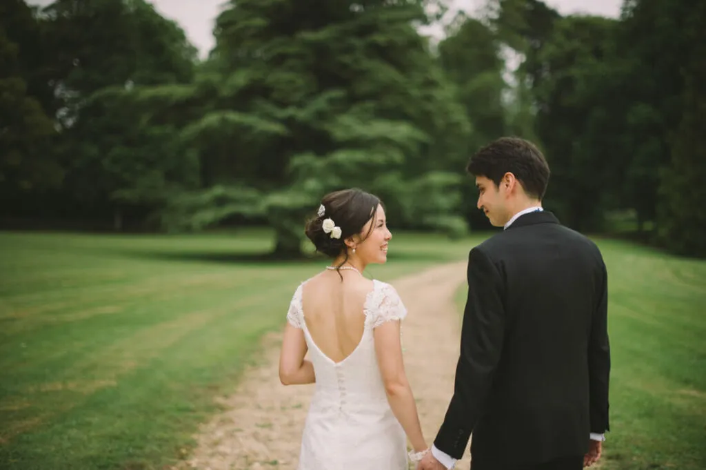 Happy bride and groom walking hand in hand down a track in an orchard.
