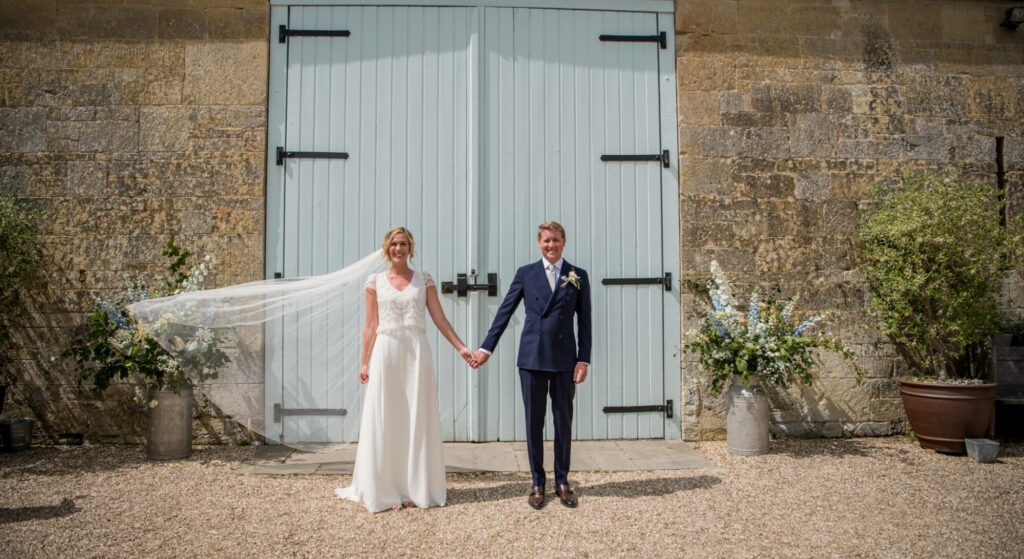 Bride and groom holding hands in a courtyard on their wedding day.