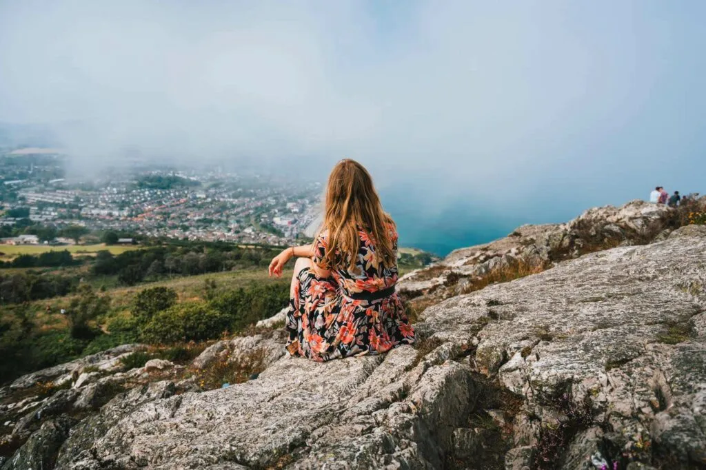 Professional makeup artist Evie Sith sitting on a high rock ledge in Costa Rica looking out at the stunning view on the horizon.